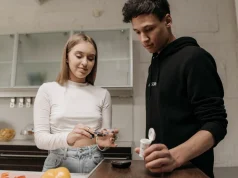 Kan Şekeri Nasıl Dengede Kalır ve Açlık, Tokluk, HbA1c Değerleri Ne Anlatır Mutfakta parmaktan kan şekeri ölçümü yapan genç kadın ve yanında duran genç erkek