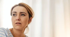 Endişeli bir ifadeyle uzaklara bakan kadın, korkunun bedende ve zihinde yarattığı tetikte olma hâli