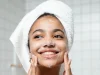 Perioral Dermatit Neden Olur ve Ağız Çevresindeki Kızarıklık Nasıl Yatışır Yüzünü yumuşak bir temizleyiciyle yıkayan, başında havlu olan genç kadın