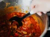 Pişmiş Yemek Oda Sıcaklığında Kaç Saat Bekleyebilir ve Sıcak Yemek Buzdolabına Nasıl Konur Ocakta bekleyen tencerede domatesli sebze yemeğinin kepçeyle karıştırılması