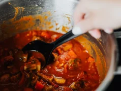 Pişmiş Yemek Oda Sıcaklığında Kaç Saat Bekleyebilir ve Sıcak Yemek Buzdolabına Nasıl Konur Ocakta bekleyen tencerede domatesli sebze yemeğinin kepçeyle karıştırılması